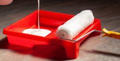 a red tray with a roll of toilet paper on top of it and a yellow handle