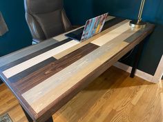 a laptop computer sitting on top of a wooden desk next to a gray leather chair