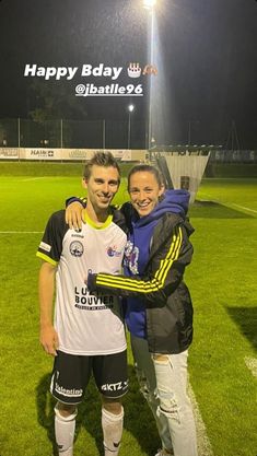 a man and woman posing for a photo on the soccer field with their arms around each other