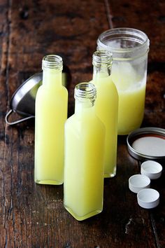 two bottles filled with lemonade sitting on top of a wooden table next to measuring spoons