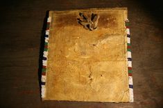 an old, worn out book on a wooden table with beaded trim around the edges