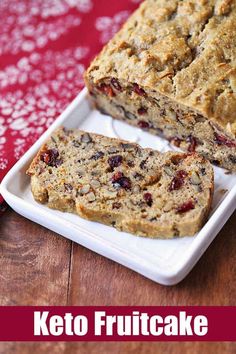 a loaf of fruitcake sitting on top of a white plate next to a red cloth