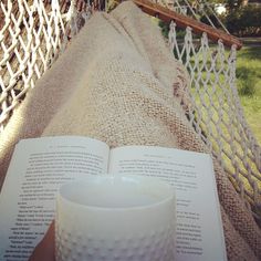 an open book and coffee cup on a hammock