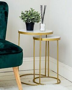 a green velvet chair next to a small table with a plant on it and a candle holder