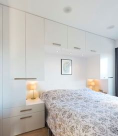 a bedroom with white cabinets and a large bed in the middle, along with two lamps on either side of the bed