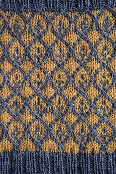 a blue and yellow knitted blanket with an intricate design on the bottom half of it