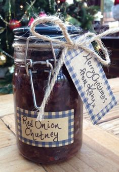 a jar filled with red onion chutney next to a christmas tree