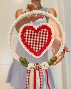 a woman holding a mirror with a red and white heart on it