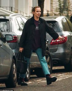 a man is walking down the street with his hand in his pocket while carrying two bags