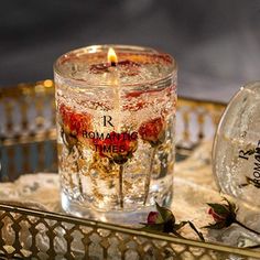 a lit candle sitting on top of a table next to a glass jar filled with liquid