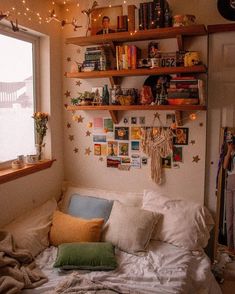 a bed with lots of pillows on top of it next to a book shelf filled with books