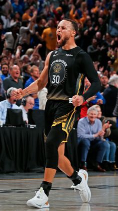 a man in black jersey and yellow shorts running on basketball court with crowd behind him