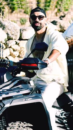 a man sitting on the back of a four - wheeler in front of some rocks