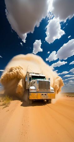 a large truck driving down a dirt road under a cloudy blue sky with white clouds