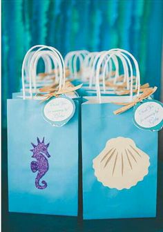 two bags with sea shells on them sitting on a table