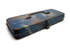 an old blue toolbox with rust on the outside and inside, sitting against a white background