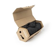 an open cardboard box with black clothing in it on a white surface and the lid opened