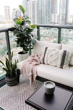 a white couch sitting on top of a balcony next to a potted plant