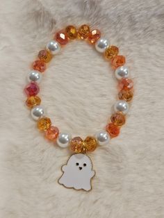 a bracelet with an orange and white beaded ghost charm on it's side