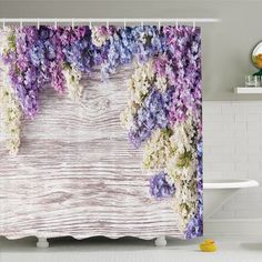 a shower curtain with purple and white flowers on the outside, in front of a bathtub