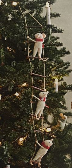 two mice are climbing up the ladder to decorate a christmas tree with candles on it