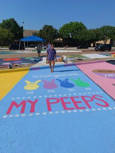 a woman walking down the sidewalk in front of a painted area that says, my pee's