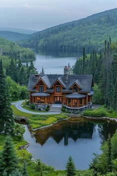 an aerial view of a house in the woods with a lake and mountains behind it