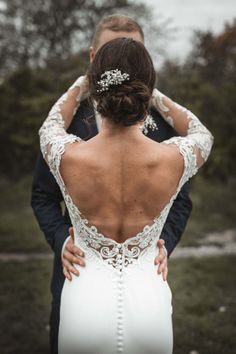 the back of a bride's dress as she stands next to her groom