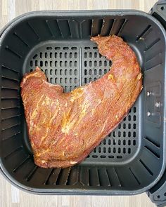 a large piece of meat sitting on top of a black plastic container with holes in it