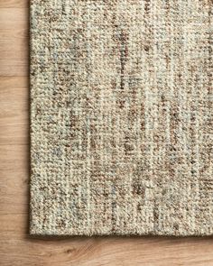 an area rug on top of a wooden floor with a white and brown color scheme