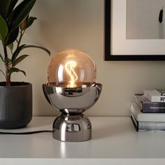 a lamp that is sitting on top of a table next to a potted plant