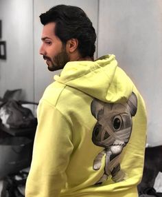 a man wearing a yellow hoodie with a koala on it's back