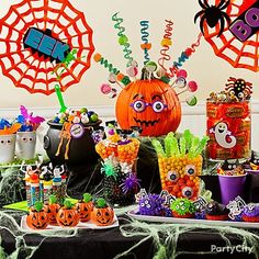 a table topped with lots of candy and halloween decorations on top of it's tables