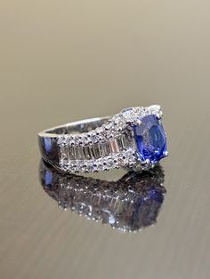 DeKara Designs Collection Metal- 18K White Gold, .750. Stones- Genuine Oval Ceylon Blue Sapphire 1.69 Carats. 38 Round Diamonds, 16 Baguette Diamonds H-I Color VS2-SI1 Color 1.09 Carats. Beautiful Art Deco Inspired Entirely Handmade Oval Shaped Ceylon Blue Sapphire Diamond Baguette Engagement Ring Created in 18K White Gold. There is a beautiful oval blue sapphire in the center of the ring that is professionally set between four prongs. The top of and the bottom of the sapphire has round prong se Blue Diamond Ring With Baguette Diamonds, Classic Blue Baguette Cut Diamond Ring, Oval Tanzanite Diamond Wedding Ring, Blue Baguette Cut Diamond Ring With Baguette Diamonds, Luxury Oval Rings With Baguette Diamonds, Luxury Baguette Cut Sapphire Ring, Blue Baguette Cut Rings With Diamond Accents, Blue Baguette Diamond Ring, Blue Diamond Ring With Baguette Cut And Accent Stones