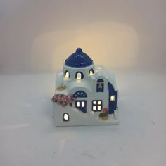 a small white and blue house with flowers on the roof is lit up at night