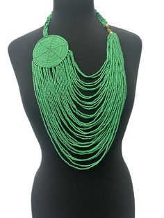 This is an authentic African necklace with a multilayered design and a large disc pendant. The necklace features gold brass and is made of green beads colour. The style of the necklace is beaded and the pendant is beautifully crafted to add to its unique appeal. The necklace is perfect for anyone who loves ethnic and regional-style jewellery. It is ideal for wearing to special occasions and events or to complete an everyday look.  Colour - Green Length - 22inches Material : Beads, Brass Traditional Green Beaded Necklaces With Dangling Beads, Traditional Green Beaded Necklace With Dangling Beads, Green Polished Beaded Necklace For Festival, Green Dangling Beads For Festival, Green Polished Beads Necklace For Festivals, Green Multi-strand Beaded Necklaces For Festivals, Green Multi-strand Jewelry With Dangling Beads, Green Multi-strand Beaded Necklace For Festival, Traditional Green Multi-strand Beads