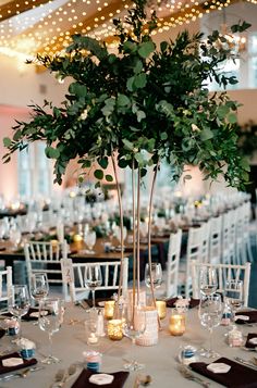 an elegant centerpiece with candles and greenery is displayed on the tables at this wedding reception