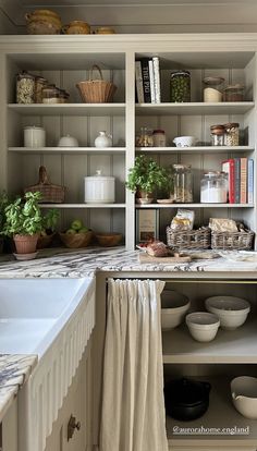 a kitchen filled with lots of white dishes and cupboards next to a counter top