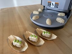 three pieces of cake sitting on top of wooden spoons next to an espresso machine