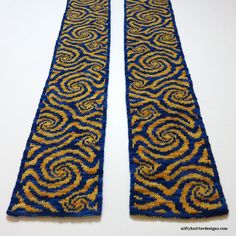 two blue and gold beaded book ends on a white surface with an intricate design in the middle