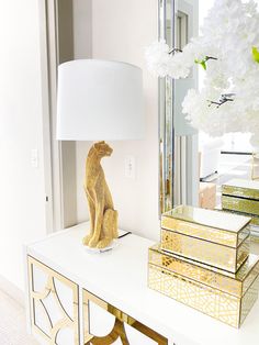 a lamp sitting on top of a white table next to a vase filled with flowers