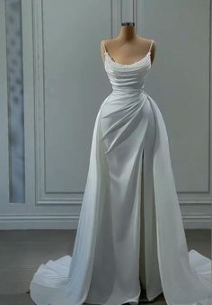 a white wedding dress on display in front of a wall and floor length mannequin