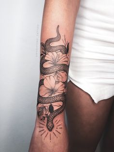 a woman's arm with a snake and flowers tattoo on the left side of her arm