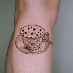 a tattoo on the leg of a woman with a cup and saucer in it