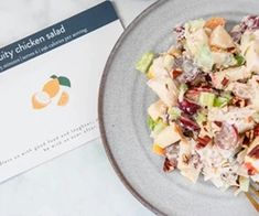 a salad on a plate next to a card with the word quality chicken salad written in it