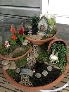 three clay pots filled with plants and small gnome figurines on top of each other