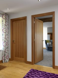 an empty room with two wooden doors and a purple rug in front of the door