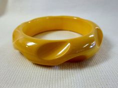 "Carved, rounded bangle bracelet in cream corn yellow. Measures 3 1/2\" across, 3/4\" thick. Simichrome tested, guaranteed to be Bakelite." Vintage Yellow Round Bracelets, Retro Yellow Bangle Bracelets, Retro Yellow Bangle Bracelet, Retro Yellow Adjustable Bracelets, Cream Corn, Bakelite Brooch, Bakelite Bracelets, Lotus Necklace, Bakelite Bangles