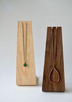 two necklaces on wooden stand with green bead hanging from it's sides