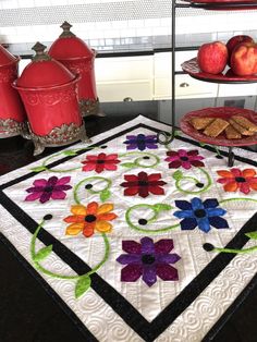 a quilted table top with apples and flowers on it